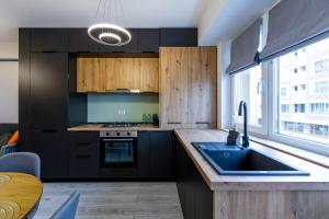 a kitchen with black cabinets and a sink at Rezidential Bacovia Orange by Rooms in Bacău