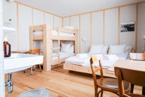 a room with two bunk beds and a table at Hôtel de la Maison de la Tourbière in Les Ponts-de-Martel