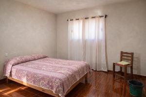 a bedroom with a bed and a chair and a window at Hospedaje Rayo De Sol in Tepoztlán