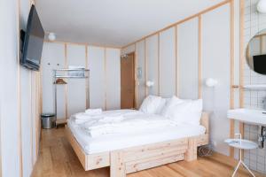 a bedroom with a white bed and a television at Hôtel de la Maison de la Tourbière in Les Ponts-de-Martel