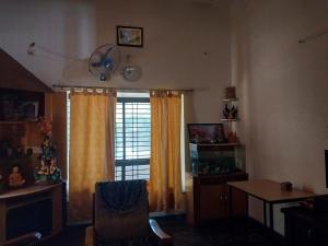 a living room with a window with curtains and a table at Saraswati Sadan in Hospet