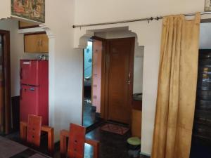 a kitchen with a red refrigerator and some chairs at Saraswati Sadan in Hospet +19 photos