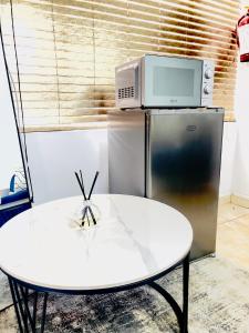 a white table with a microwave on top of a refrigerator at Genza Guesthouse in Pretoria in Pretoria