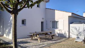 a wooden picnic table next to a white building at Maison avec Jardin privé in Saint-Hilaire-de-Riez