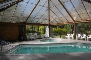 a swimming pool in a pavilion with chairs and a table at Hostería Millahue in San José de Maipo