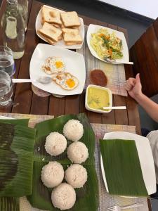 a table with plates of food and eggs and bread at Senaya Homestay in Belihuloya