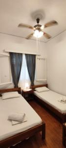 two beds in a room with a ceiling fan at Dandelion Paros Apartments IV in Kóstos
