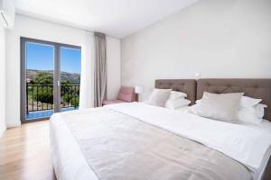 a white bedroom with a large bed and a balcony at Villa High Life in Seget Vranjica +18 photos