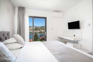 a white bedroom with a large bed and a television at Villa High Life in Seget Vranjica