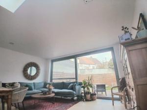 a living room with a blue couch and a large window at Mi casa es su casa in Ghent