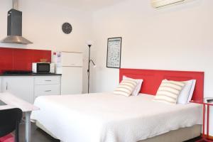 a bedroom with a white bed and a red headboard at Faial Marina Apartments 1 in Horta