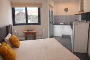 a room with a bed and a kitchen with a refrigerator at Faial Marina Apartments 1 in Horta