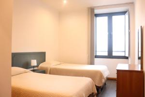a hotel room with two beds and a window at Faial Marina Apartments 1 in Horta +70 photos