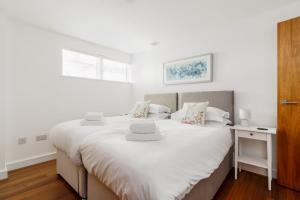 a bedroom with a bed with white sheets and a window at A Wave From It All - Extensive Harbour Views from Wrap-Around Balcony in Poole