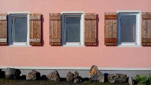 a pink wall with windows and rocks at Faial Cottage in Cedros +12 photos