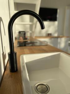 a kitchen sink with a black faucet on a counter at The Conservatory, a cosy holiday home located central between Gent Antwerpen & Brussel in Lokeren +26 photos