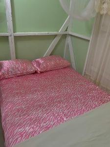 a bed with a pink comforter in a room at Minos Haven in Trafalgar