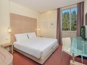 a bedroom with a large white bed and a window at B&B HOTEL Calenzano First in Calenzano +24 photos