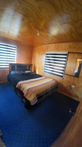 a bedroom with a bed in a wooden room at Cabaña con tinaja Aucaco in Ancud