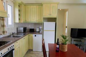a kitchen with yellow cabinets and a white refrigerator at Villa Nefeli Breeze in Dassia