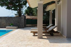 a swimming pool with a chair next to a house at Villa Nefeli Breeze in Dassia