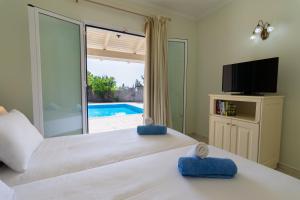 a bedroom with a large bed with a tv and a window at Villa Nefeli Breeze in Dassia
