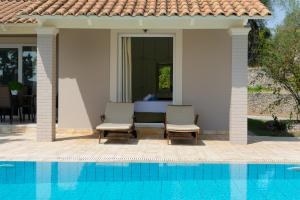 a patio with two chairs next to a swimming pool at Villa Nefeli Breeze in Dassia