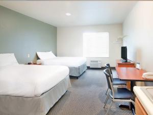 
a hotel room with two beds and a desk at WoodSpring Suites Dickinson in Dickinson
