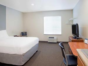 ein Hotelzimmer mit einem Bett, einem Schreibtisch und einem TV in der Unterkunft Suburban Studios in Dickinson