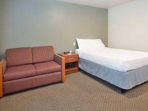 
a hotel room with a couch, chair and a television at WoodSpring Suites Dickinson in Dickinson
