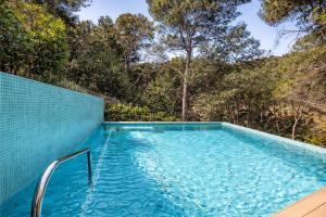 a swimming pool with a blue wall and trees at Seren Casa Begur - Illa Roja Beach in Begur