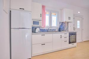 a kitchen with white cabinets and a white refrigerator at Beachside Bungalows Acharavi Corfu in Acharavi