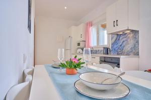 a white kitchen with a table with glasses and a bowl at Beachside Bungalows Acharavi Corfu in Acharavi