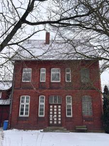 a red brick house with snow on the ground at Emmerstedt - Alte Schule in Helmstedt