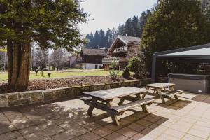 two picnic tables sitting on a patio in front of a building at La Charbonnière, grand gîte haut-de-gamme avec jacuzzi et sauna in Gérardmer