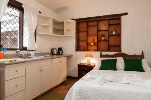 a bedroom with a bed and a kitchen with a sink at Apartamentos Otorongo Cuenca Ecuador in Cuenca