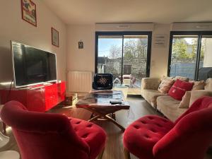 a living room with two red chairs and a television at Les cabines de Granville in Granville