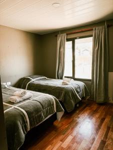 two beds in a room with a window at Cabañas Lihuen in Caviahue