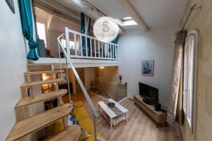 a living room with a staircase and a tv at La Pitchoune Arles Centre in Arles