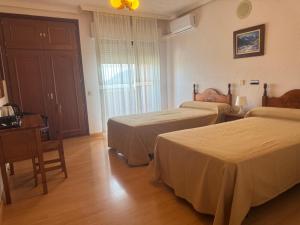 a hotel room with two beds and a table at Hotel Dracos in Cebreros +3 photos