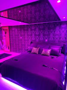 a purple bedroom with a large bed with purple lighting at Loveroom LovaLova in Reims +33 photos