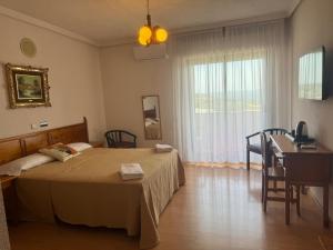 a bedroom with a bed and a table and a window at Hotel Dracos in Cebreros