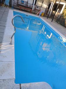 a blue swimming pool with a metal railing in a building at Depto Castillo in El Bolsón +2 photos