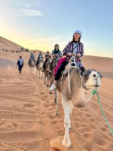 a group of people riding on a camel in the desert at Royal Erg Chebbi Luxury Camp in Adrouine +21 photos