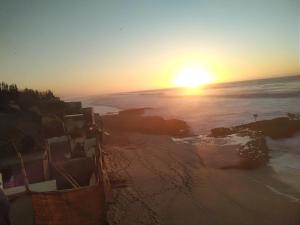 a sunset over the ocean and a beach with buildings at Grotte Panoramique Atlantique d'Aglou in Zaouia Sidi Ouaggag