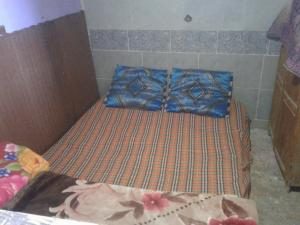 a small bed with a blue pillow on it at Grotte Panoramique Atlantique d'Aglou in Zaouia Sidi Ouaggag