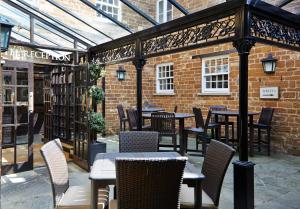 a patio with tables and chairs in a brick building at Saracens Head Hotel by Greene King Inns in Towcester