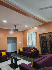 a living room with purple couches and a tv at Gifted Estates in Accra
