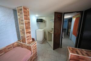 a small room with a brick fireplace and a bathroom at Pousada do Sergio in Barra de Guaratiba