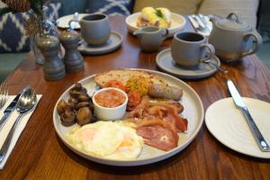 a wooden table with a plate of breakfast food at Saracens Head Hotel by Greene King Inns in Towcester +17 photos